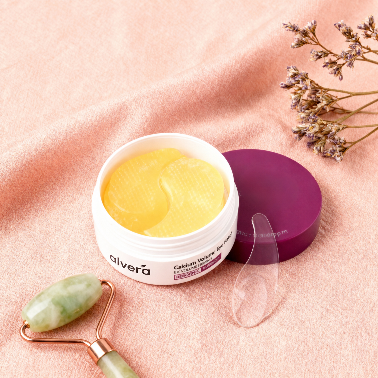 Open tub of Alvera Calcium Volume Eye Patches with a jade roller